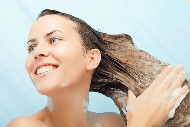 Beautiful young woman enjoying the shower, washing her long hair.